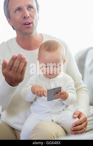 Padre Felice e la sua bimba giocando con il telefono cellulare sul lettino