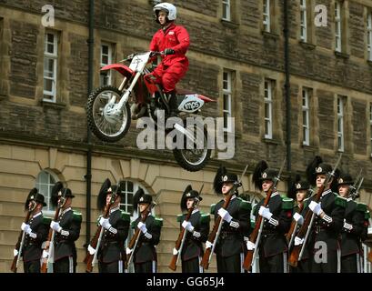 Il PIM Display moto Team salto oltre i membri del team di perforazione da Sua Maestà il Re guardia della Norvegia durante una prova per questo anno la Royal Edinburgh Tattoo militare a Redford caserma di cavalleria di Edimburgo. Foto Stock