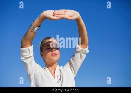 Giovane donna in piedi con gli occhi chiusi contro il cielo blu Foto Stock