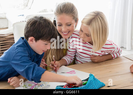 Madre e bambini facendo i compiti sul tavolo Foto Stock