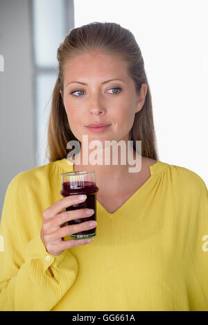 Bella donna tenendo un bicchiere di succo di frutta Foto Stock
