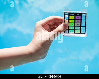 Controllare l'inquinamento delle acque in blu piscina esterna dal tester di chimica Foto Stock