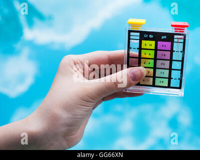 Controllare il livello del pH in blu piscina esterna dal tester di chimica Foto Stock