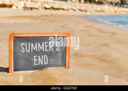 Primo piano di una lavagna con il testo estati fine scritto in esso, sulla sabbia di una spiaggia Foto Stock