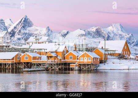 I colori dell'alba telaio le case di pescatori circondato dal mare ghiacciato, Sakrisoy nei, la Reine, Nordland, Isole Lofoten in Norvegia Foto Stock