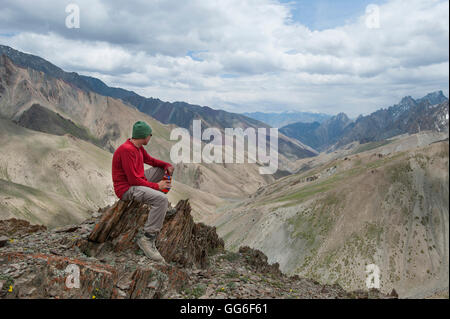 Un trekker si ferma ad ammirare il panorama dalla cima del Konze La nella remota regione himalayana del Ladakh, India Foto Stock