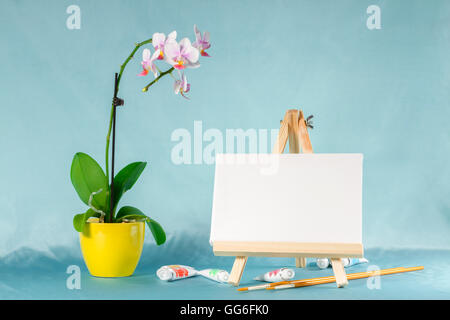 Ancora in vita con cavalletto con una tela vuota, acquarello e fiori di orchidea Foto Stock