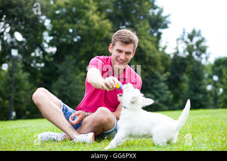 Giovane uomo giocando con il suo cane in estate park Foto Stock