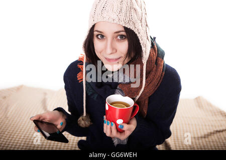 Donna godendo di una tazza grande di preparato di fresco tè caldo come lei si rilassa su un divano nel soggiorno Foto Stock