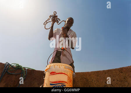 L'uomo il recupero di acqua da un pozzo nella regione del Sahel del fiume Senegal, Senegal Foto Stock