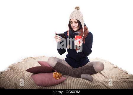 Foto morbido della donna sul letto con la tavoletta e la tazza di tè o caffè in mani, alto punto di vista Foto Stock