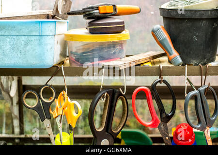 Tettoia da giardino Utensili a mano o forbici appesi in una fila su un ripiano Foto Stock