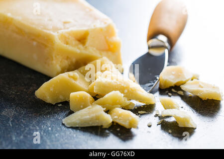 Il formaggio parmigiano con coltello sul vecchio tavolo da cucina. Foto Stock