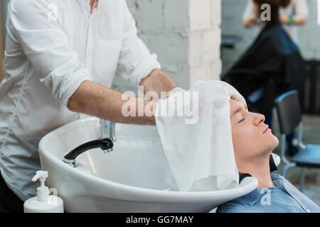 Vista di profilo di un giovane uomo di prepararsi per i suoi capelli lavati Foto Stock