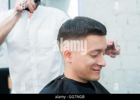 Barbiere maschio dando Haircut Client in negozio Foto Stock