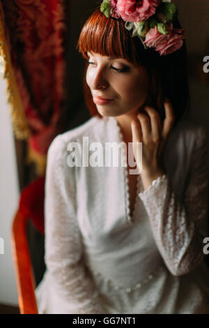 Giovane sposa con matrimonio Trucco e acconciatura in camera da letto, attraente donna sposi hanno preparato finale, aspettando lo sposo. Foto Stock