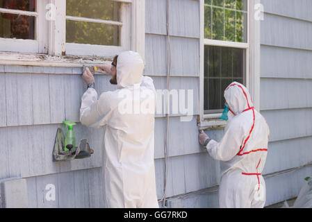 Casa due pittori in hazmat adatta per la rimozione di vernice di piombo da una vecchia casa. Foto Stock