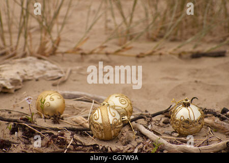 Natale decorativo baubles disposti in sabbia con driftwood su una spiaggia in Nuova Zelanda per un estate Emisfero Sud Xmas Foto Stock