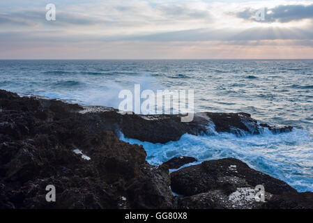 Sera seascape vista dalla riva con raggi di sole nel cielo nuvoloso. Foto Stock