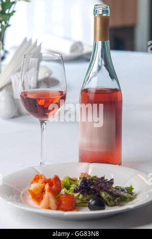 Insalata di pesce e un bicchiere di vino rosato in un ristorante Foto Stock