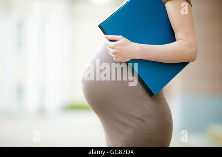 Attiva il concetto di gravidanza. Close-up di pancia di happy business  giovane donna incinta in piedi sulla strada con la cartella Documenti Foto  stock - Alamy