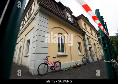 Witzenhausen, Germania. 10 Ago, 2016. Moto può essere visto dietro le linee della polizia in un edificio che fu sede dei rifugiati in Witzenhausen, Germania, 10 agosto 2016. Un incendio nel seminterrato del rifugiato la scorsa notte a sinistra 22 residenti sono stati leggermente. Foto:SWEN PFOERTNER/dpa/Alamy Live News Foto Stock