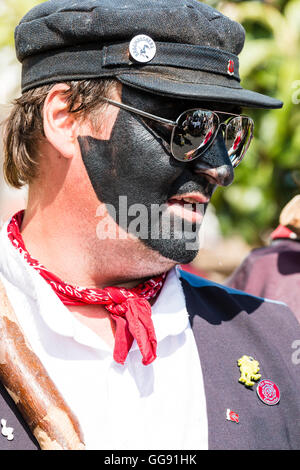 Broadstairs settimana della musica folk festival. Close up ritratto, testa e spalle, uomo caucasico con il volto dipinto di nero. 'Dead cavallo e Broomdashers' morris uomini gruppo. Indossare occhiali a specchio. vista laterale. Foto Stock