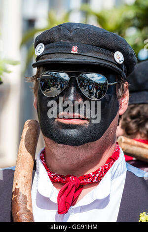 Broadstairs settimana della musica folk festival. Close up ritratto, testa e spalle, uomo caucasico con il volto dipinto di nero. 'Dead cavallo e Broomdashers' morris uomini gruppo. Indossare occhiali a specchio. Di fronte. Foto Stock