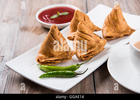 Samosa snack di ketchup e tè caldo, fresco samosas con ketchup e caldo chai pronti per la prima colazione Foto Stock