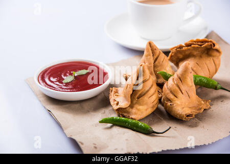 Samosa snack di ketchup e tè caldo, fresco samosas con ketchup e caldo chai pronti per la prima colazione Foto Stock