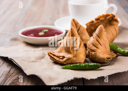 Samosa snack di ketchup e tè caldo, fresco samosas con ketchup e caldo chai pronti per la prima colazione Foto Stock