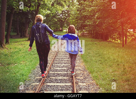 Una bambina e sua madre in equilibrio su rotaie. Foto Stock