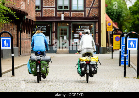 Ystad, Svezia - 1 Agosto 2016: persone reali nella vita di tutti i giorni. Due turisti in viaggio in bici visto da dietro con pacchetti completi o Foto Stock