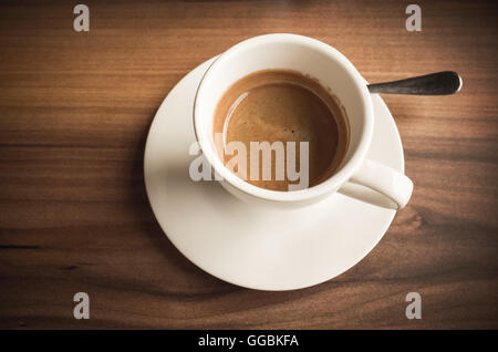 Caffè appena macinato di caffè nella tazza bianca sul tavolo di legno. Primo piano con il fuoco selettivo Foto Stock