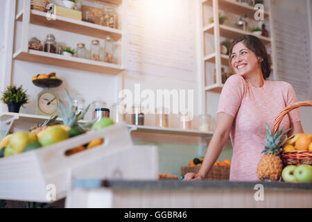Ritratto di giovane e bella donna in piedi dietro il bancone del suo bar con succhi. Femmina caucasica lavorando a un juice bar cercando Foto Stock