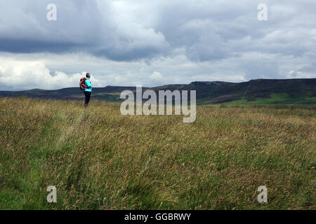 Femmina solitario escursionista si ferma a guardare il cielo presagio mentre passeggiate nel Parco Nazionale di Peak District, England, Regno Unito Foto Stock