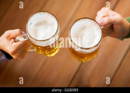 Stretta di mano con boccali da birra presso il bar o pub Foto Stock