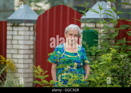 Una donna anziana si erge all'esterno. Foto Stock