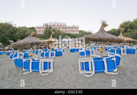 Canyamel spiaggia sabbiosa con blue sedie a sdraio e hotel in background in una serata estiva in Canyamel, Maiorca. Foto Stock