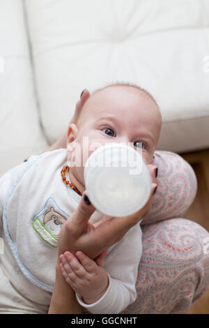 Madre dà baby bere latte da una bottiglia Foto Stock
