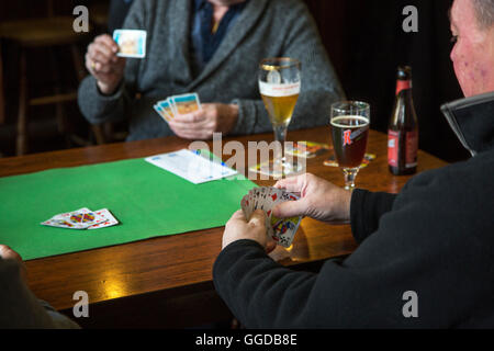 Scheda anziani giocatori che giocano le carte in tavola in pub Foto Stock