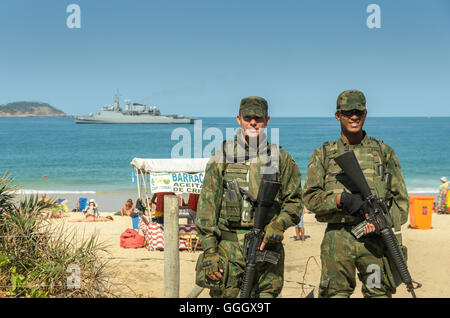 Il brasiliano della polizia militare guardare oltre i turisti e i locali presso la spiaggia di Ipanema a Rio de Janeiro durante il Rio 2016 Foto Stock