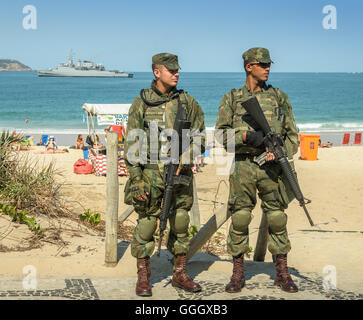 Il brasiliano della polizia militare guardare oltre i turisti e i locali presso la spiaggia di Ipanema a Rio de Janeiro durante il Rio 2016 Foto Stock