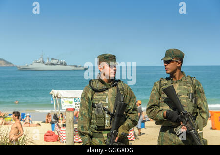 Il brasiliano della polizia militare guardare oltre i turisti e i locali presso la spiaggia di Ipanema a Rio de Janeiro durante il Rio 2016 Foto Stock