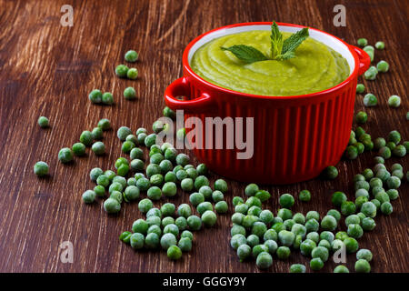 Ciotola di sano pisello verde zuppa su tavola in legno rustico Foto Stock