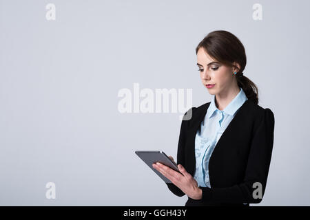 Una donna d'affari si concentra mentre lavora sul suo tablet dati. Immagine Studio su sfondo bianco con spazio di copia a sinistra dell'immagine Foto Stock