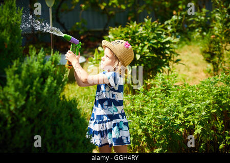 Poco felice ragazza giardino di irrigazione Foto Stock