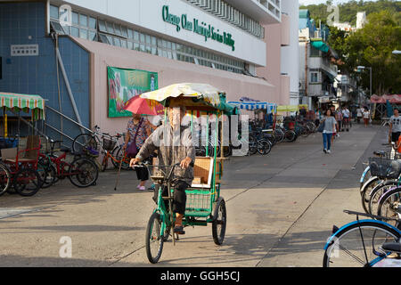 Un'anziana donna cinese passato i cicli di mercato In Cheung Chau, Hong Kong. Foto Stock