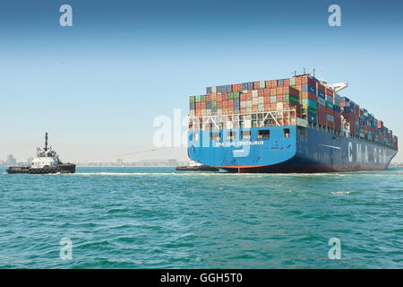 Il Gigante, CMA CGM Centauro, contenitore di nave è manovrato verso il molo J nella lunga spiaggia di terminal per container, Los Angeles, California, USA. Foto Stock