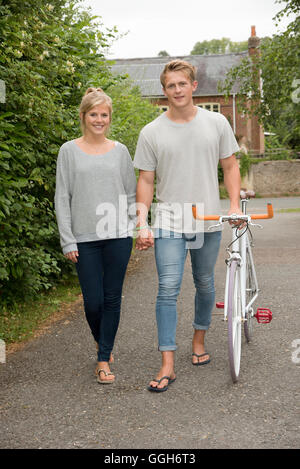 Coppia giovane tenendo le mani a camminare su una strada di campagna Foto Stock